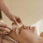 A calming side view of a woman receiving a gua sha facial massage indoors, promoting healthy skin.