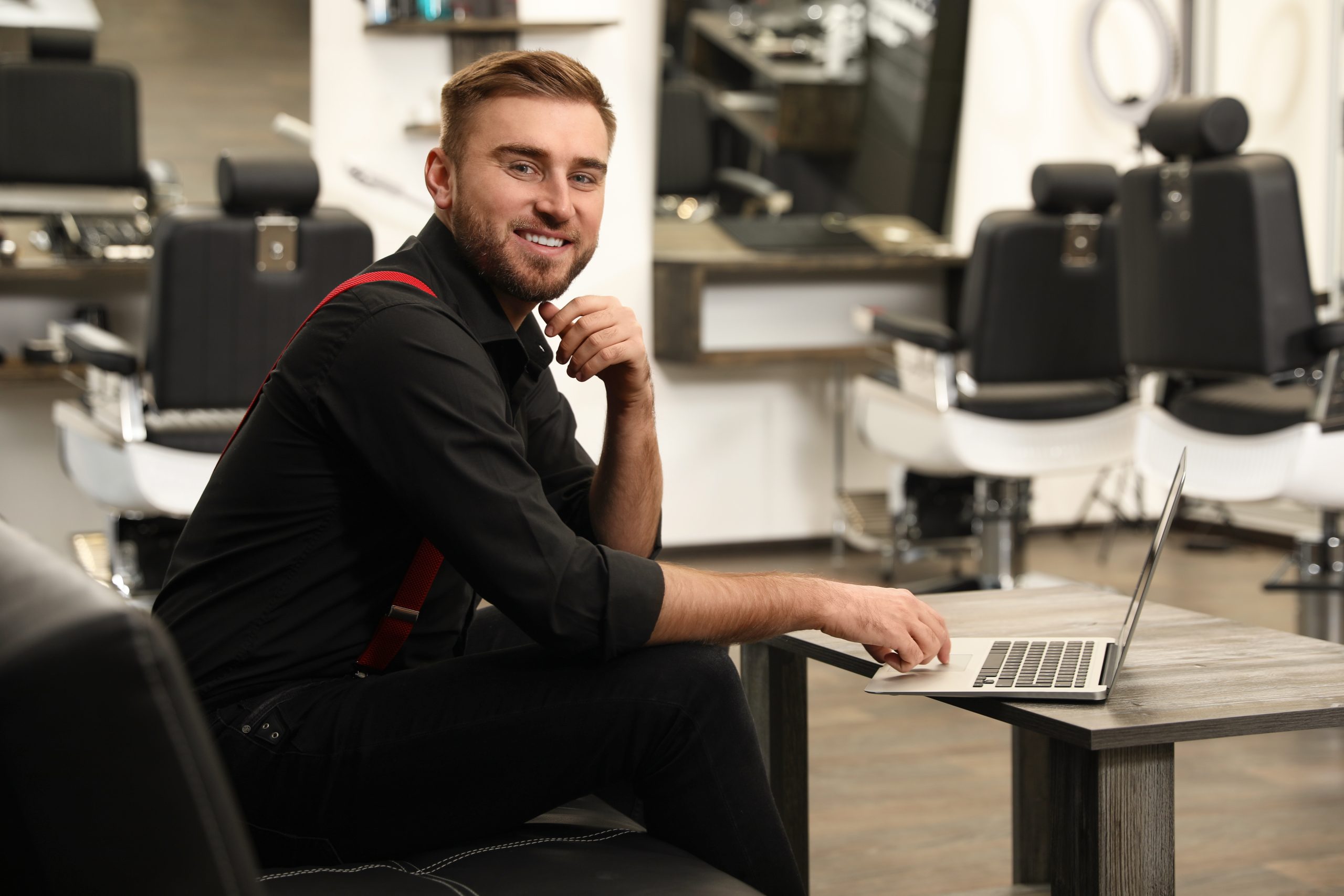 A salon owner managing his diary on a laptop